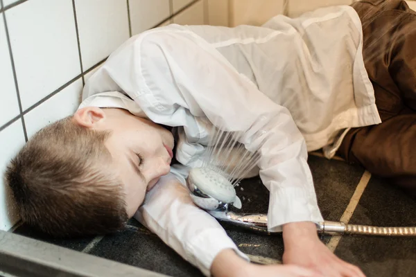 Fully clothed boy unconscious on shower floor — Stock Photo, Image