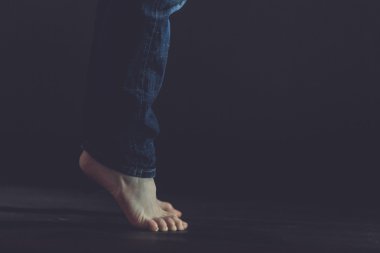 Close up of bare feet standing on dark floor clipart