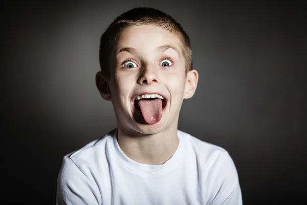 Goofy mannelijk kind maken van gezichten in verduisterde kamer — Stockfoto