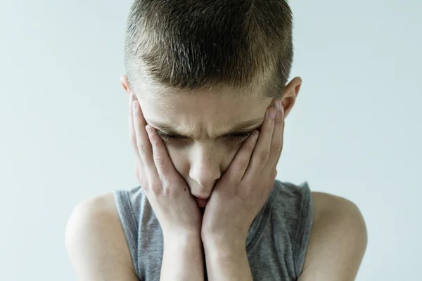 Onrustige jonge jongen gezicht bedrijf in handen — Stockfoto