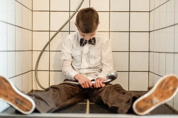 V bezvědomí chlapec s běžící Sprchová hlavice — Stock fotografie