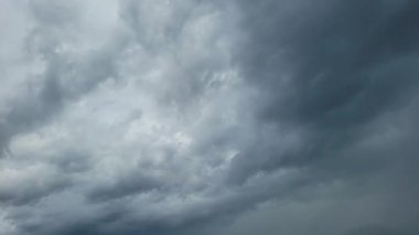 Video koyu gri fırtına bulutlarının sürekli hareket ettiğini, gökyüzünde kaydığını ve şekil değiştirdiğini, dinamik ve yoğun bir atmosferik ekran oluşturduğunu gösteriyor..