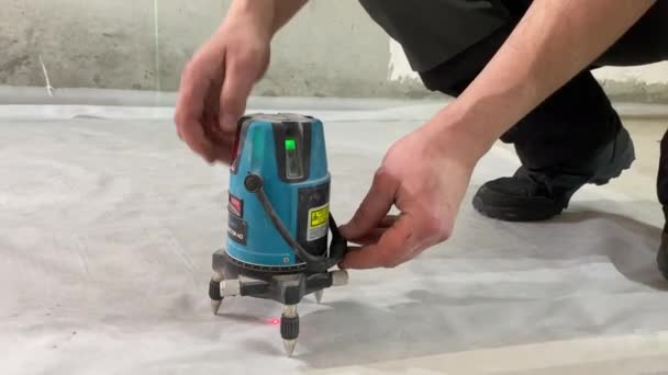 Arbeiter dreht an Laser-Niveaugerät Zement Boden Messmarken Renovierung Baustelle — Stockvideo