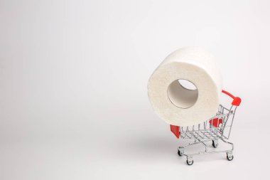 Beyaz arka planda oyuncak bir tramvayda tuvalet kağıdı rulosu. Yakın plan. Karantina sırasında paniğe kapılmış tuvalet kağıdı alımı. Coronavirüs salgınından dolayı depolama konsepti