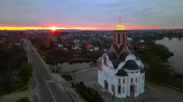 The camera circles around a small church on the river bank in a small european city at bright sunset, HDR footage — Vídeos de Stock