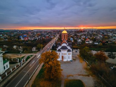 Ukrayna 'nın Kyiv bölgesi destansı günbatımında, küçük Avrupa kentinde nehir ve köprü yakınlarındaki eski kilisenin HDR hava görüntüsü