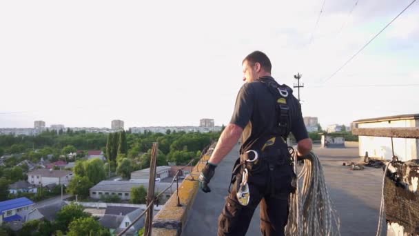 Industriekletterer wirft das Seil auf einer Baustelle eines Hochhauses herunter. Gefährliche Arbeit in Höhenlagen. Zeitlupenaufnahmen — Stockvideo
