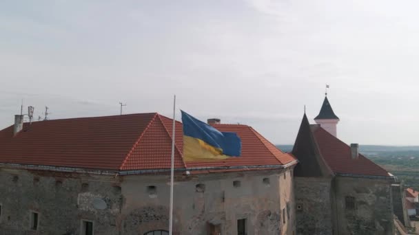 Bandera de Ucrania ondea en la pared de un antiguo castillo medieval en la pequeña ciudad europea — Vídeo de stock