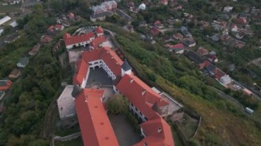 İnsansız hava aracı bulutlu bir sonbahar gününde Avrupa 'nın küçük bir şehrindeki dağdaki ortaçağ şatosunun üzerinde uçuyor.