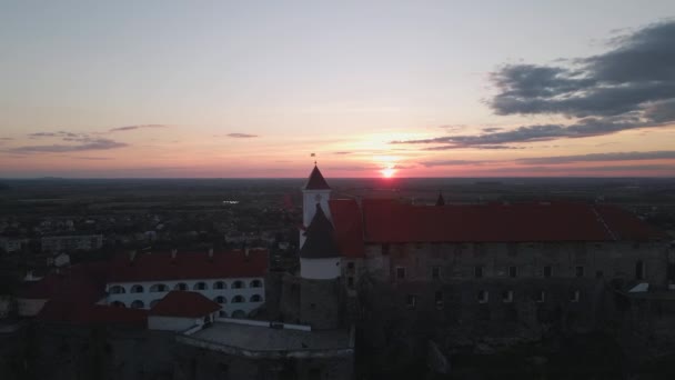 Letecký pohled na středověký hrad na hoře v malém evropském městě při jasném podzimním západu slunce — Stock video