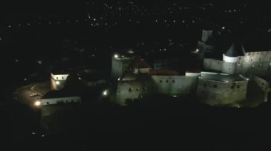 Avrupa 'nın küçük bir şehrinde sonbahar gecesi dağdaki aydınlık ortaçağ şatosunun havadan görünüşü