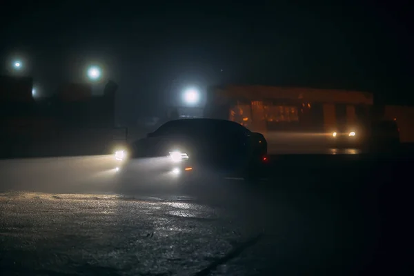 Coche deportivo en las sombras con luces brillantes en poca luz en la noche de niebla, o silueta de fondo oscuro coche deportivo. Enfoque selectivo Fotos de stock libres de derechos