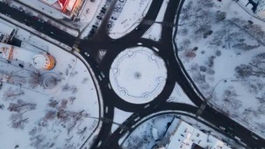 Kış günü Avrupa 'da küçük bir şehir olan ve karla kaplı yuvarlak arabalı 4K' lık kavşak yolu manzarası hızlanıyor.