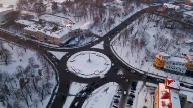 Kış günbatımında küçük Avrupa kenti karla kaplı yuvarlak arabalı 4K 'lık kavşak yolu manzarası