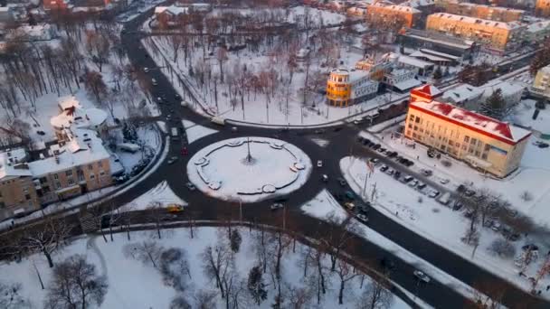 4k εναέρια άποψη του κυκλικού δρόμου με κυκλικά αυτοκίνητα στο χιόνι καλύπτονται μικρή ευρωπαϊκή πόλη το χειμώνα ηλιοβασίλεμα — Αρχείο Βίντεο