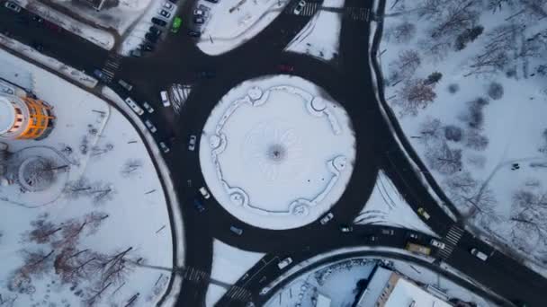 4k luchtfoto van rotonde weg met cirkelvormige auto 's in besneeuwde kleine Europese stad in de winter dag, versnellen — Stockvideo
