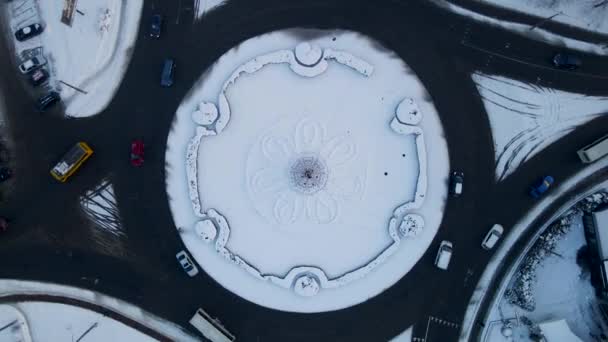 4k aerial view of roundabout road with circular cars in snow covered small european city at winter day, speed up — Stock Video