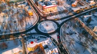Güneşli kış gününde, küçük Avrupa şehrinde yuvarlak arabalı yuvarlak kavşaklı yolun 4k hava manzaralı zaman çizelgesi.