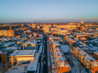 Kışın güneşli bir günde karla kaplı çatıları olan küçük Avrupa şehrindeki hava manzaralı yol