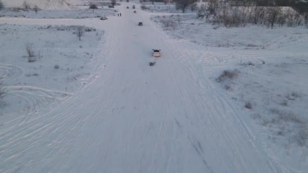 Человек катается на лыжах с веревкой за машиной по снежной дороге, замедленная съемка — стоковое видео