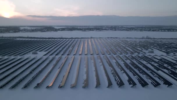 El avión no tripulado vuela sobre Solar Farm. Energía verde renovable y tecnología eléctrica. Campo de paneles solares se encuentra en una fila en los campos para la producción de energía al atardecer de invierno. Concepto de energía verde. — Vídeo de stock
