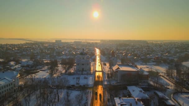 Drone vliegen boven de weg op besneeuwde kleine Europese stad in de winter zonsondergang, HDR — Stockvideo
