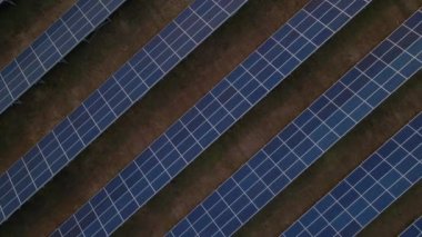 Bahar sabahının erken saatlerinde bir güneş çiftliğindeki büyük güneş panellerinin yukarıdan aşağıya doğru görüntüsü. Güneş pili santralleri. görüntüler 4k.