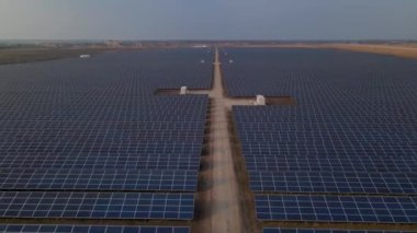 Hava aracı güneş batımında güneş çiftliğindeki büyük güneş panellerine bakıyor. Güneş pili santralleri. görüntüler 4k.