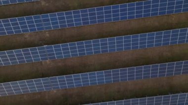 Bahar sabahının erken saatlerinde bir güneş çiftliğindeki büyük güneş panellerinin yukarıdan aşağıya doğru görüntüsü. Güneş pili santralleri. görüntüler 4k.