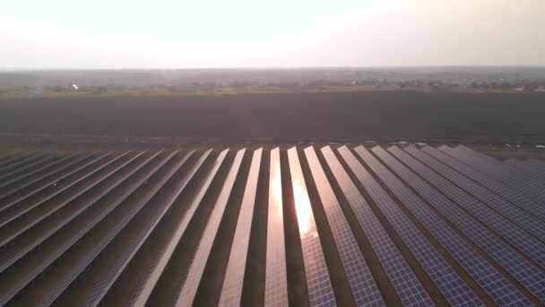 Z lotu ptaka widać duże panele słoneczne na farmie słonecznej wczesnym wiosennym zachodem słońca. Elektrownie słoneczne. materiał wideo 4k. — Wideo stockowe