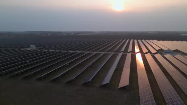 O drone sobrevoa a Solar Farm. Energia verde renovável e tecnologia elétrica. Campo de painéis solares está em uma fileira nos campos de produção de energia no dia ensolarado. Conceito de energia verde. — Vídeo de Stock