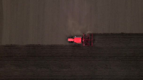 Сільськогосподарський червоний невеликий трактор в польових оранках, працює в полі. Політ над трактором, що працює в полі. Трактор плутає польовий вигляд з повітря . — стокове відео