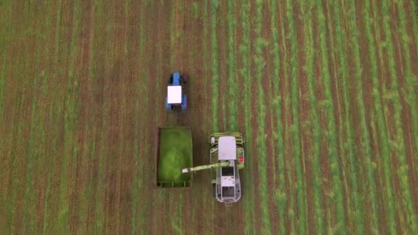 Slow motion Luchtfoto van de moderne oogstmachine laden van gerst op trekker aanhangwagens. Concept van: Tractor, Oogst, Drone b-roll beelden, Eco. — Stockvideo