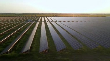 Hava aracı güneş batımında güneş çiftliğindeki büyük güneş panellerine bakıyor. Güneş pili santralleri. görüntüler 4k.