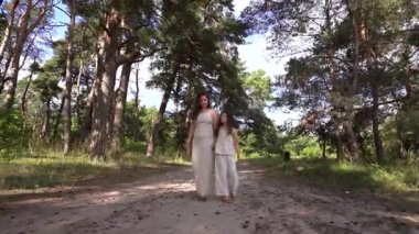 Mutlu aile annesi ve kızı orman yolunda yürüyor. çocuk rüyası konsepti. Ormanda gezen mutlu aile, dost canlısı bir aile. Yaşam tarzı anne ve kızı doğada dinleniyor.