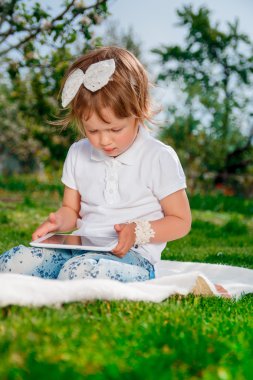 Küçük bebek kız beyaz polo ve kot pantolon giymiş. Bir Tablet kullanan kız. Tablet ile küçük kız çalışmaları