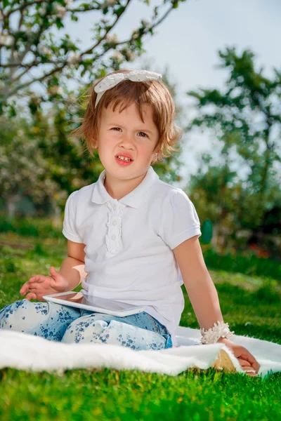 Bambina vestita di polo bianca e jeans.Girl Utilizzando una tavoletta. Ragazzina studia con la compressa — Foto Stock