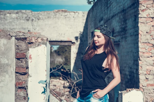 Atractiva mujer en traje de jean y taza posando en la vieja casa de fábrica en ruinas — Foto de Stock