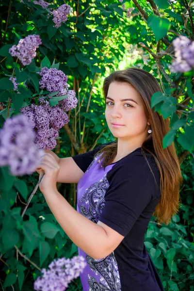 Retrato de bela, de cabelos longos, menina de cabelos escuros em vestido roxo em árvores florescentes — Fotografia de Stock