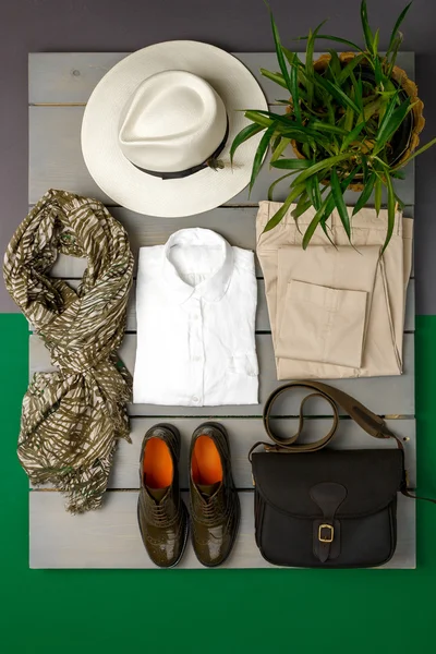 Women's outfit on wooden background. fashion clothes. beige straw hat,  pant, white shirt, green scarf black crossbody bag and oxford shoes near flower pot. Top view. — Φωτογραφία Αρχείου