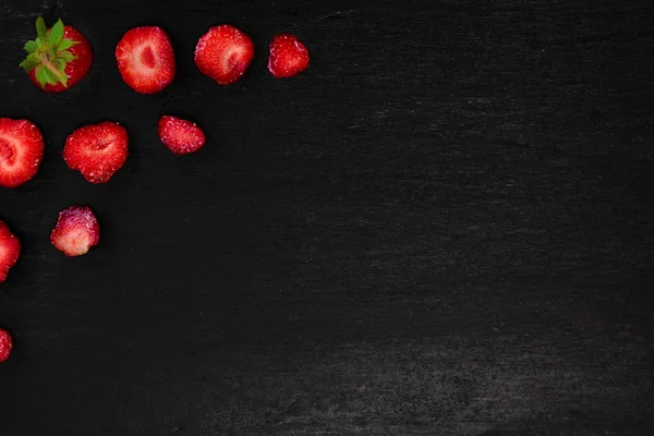 Siyah arka plan üzerinde yaprakları ile dilimlenmiş çilek. Üst görünüm, çerçeve. Kopya alanı. Yaz meyve gıda .