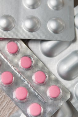 Gri ahşap arka plan üzerinde yukarıdan blister paketi ilaç ve haplar. Üstte görüş, yakından. Ağrı kesiciler, tabletler, jenerik, ilaçlar. 
