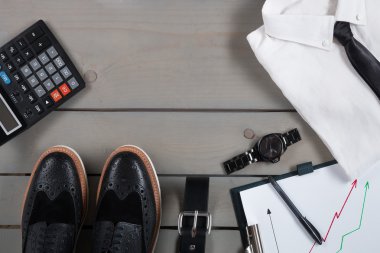 İşadamı, gri ahşap arka plan üzerinde iş kıyafeti. Siyah kravat, saat, kemer, oxford ayakkabı, planchette ve hesap makinesi ile beyaz gömlek. Geri dönelim. Alanı kopyala, çerçeve. Erkek moda aksesuarları seti.