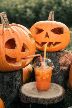 Arka planda kabak dekorasyon yakınında Cadılar Bayramı kokteyli. Bir parti için yumruk. İki Jack-o-Lantern içiyor. Tonlu fotoğraf.