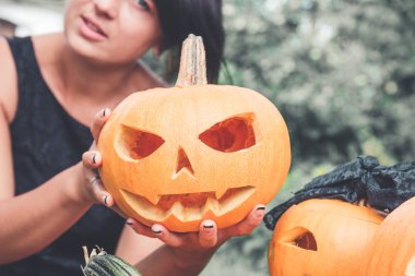 Balkabağının yanında tanınmayan bir kadın elinde bir jack-o-fener tutuyor. Halloween. Parti için dekorasyon. Yakından kapatın. Tonlu fotoğraf.