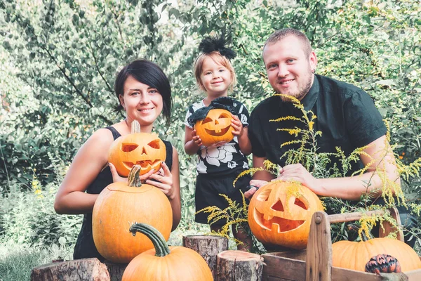 Jack-o-Lantern süslemeleri yakınındaki bahçede Cadılar Bayramı için aile hazırlığı. Mutlu. Baba, anne ve kabak ile kızı .