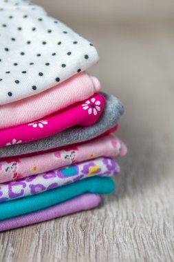 Kumaş dikiş. Pembe ve beyaz gömlek BT gri ahşap arka plan üzerinde katlanmış. Yeni doğmuş kız bebek bezi. Bebek Giyim yığını. Çocuk kıyafeti. Yakın çekim. 