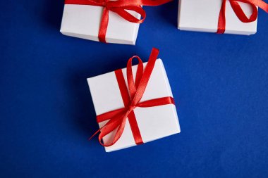 Mavi renkli arka planda kırmızı kurdeleli lüks beyaz hediye kutuları. Sevgililer günü, Noel, doğum günü hediyeleri. Babalar günü. Düz yatıyordu. Uzayı kopyala Üst görünüm.
