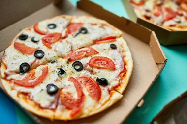 Yeşil zemin üzerinde sıcak İtalyan dilimlenmiş pizzayla açılan kutu, lezzetli fast food, teslimat konsepti, üst görünüm, fotokopi alanı, düz konum.