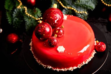 Mousse Noel pastası tatlı kırmızı ayna jölesiyle kaplanmış çelenklerle süslenmiş yeni yıl lambaları koyu arka plan, modern Avrupa pasta teması Noel teması.